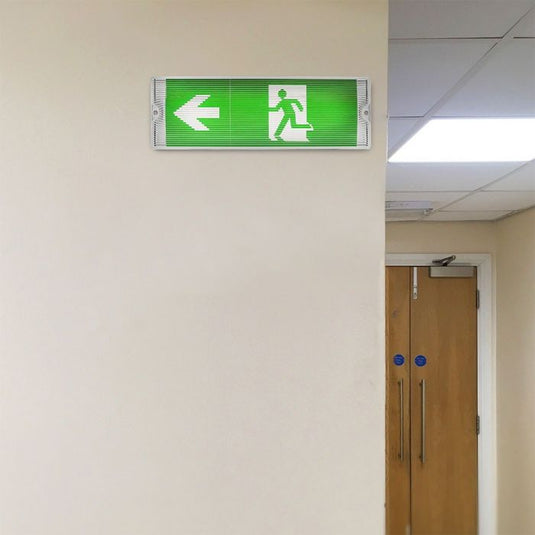 Lit exit sign with left arrow in a hallway