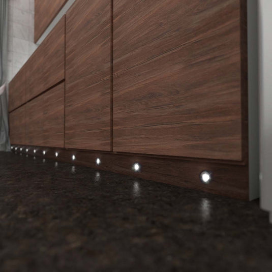 Kitchen cabinet plinth lit by round LED plinth lights, side view