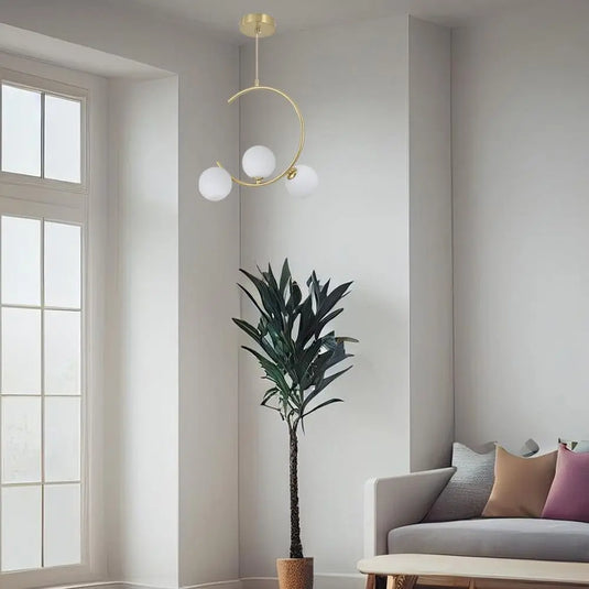 Crescent Shaped Pendant Light with Three Glass Spheres Mounted On Top Of A Living Room Setting