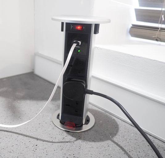 pop up electrical socket with with a sliver top and plug in cables